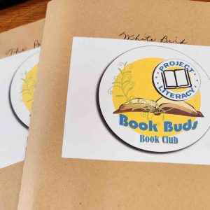 Close-up of two Project Literacy “Book Buds Book Club” folders with the Project Literacy logo, placed on a table.