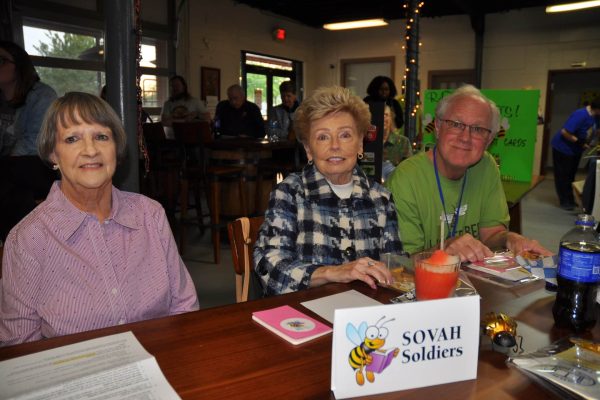 SOVAH Soldiers team members sit at their table with event materials during Danville Project Literacy’s JeopardBee fundraiser.