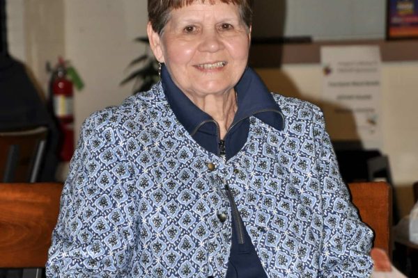 Guest smiles while seated at a table during Danville Project Literacy’s JeopardBee event.